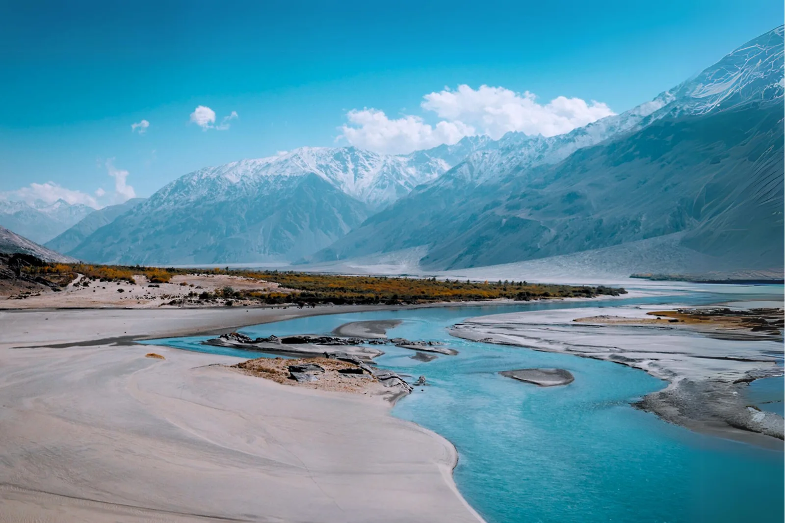 A braided river winding through a mountain valley towards distant snow-covered peaks